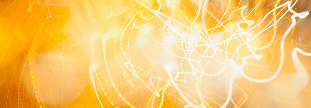 Abstract image featuring bright, swirling white and yellow light streaks against a warm, golden background, creating a vibrant and dynamic visual texture.