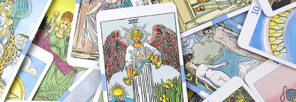 Symbolising temptations: A collection of tarot cards spread out, featuring an angel on the central card with red wings and a sun disc above its head. The card displays the Roman numeral XIV, and various other cards with different illustrations are visible around it.