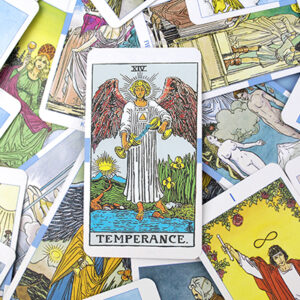 A tarot card reading setup features the Temperance card on top, depicting an angel with wings pouring liquid between two cups. The card is surrounded by various other colorful tarot cards in the spread.