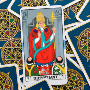 A tarot card, the Hierophant, depicting a figure in a red robe with a triple crown, holding a scepter, and two followers kneeling before them. The card is surrounded by other cards with a decorative back design.