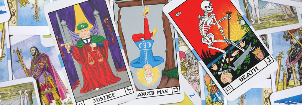 A close-up of tarot cards featuring Justice, The Hanged Man, and Death laid out on top of other scattered tarot cards with detailed illustrations.